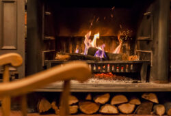 Home comfort. Rocking chair near the fireplace. Photo of interior of room. Rocking chair in the living room with decorated modern fireplace